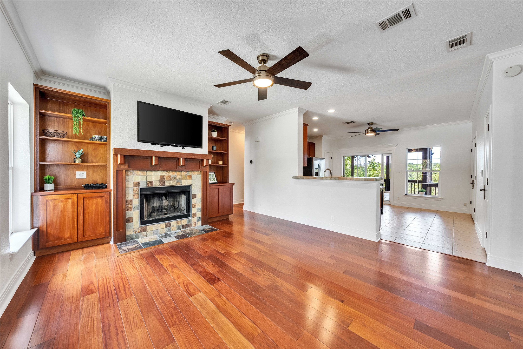 2108 Indian Creek Road Austin, TX 78734 - Photo 4 of 40 Unfurnished living room featuring ornamental molding, a fireplace, a ceiling fan, light wood-style floors, and built in features