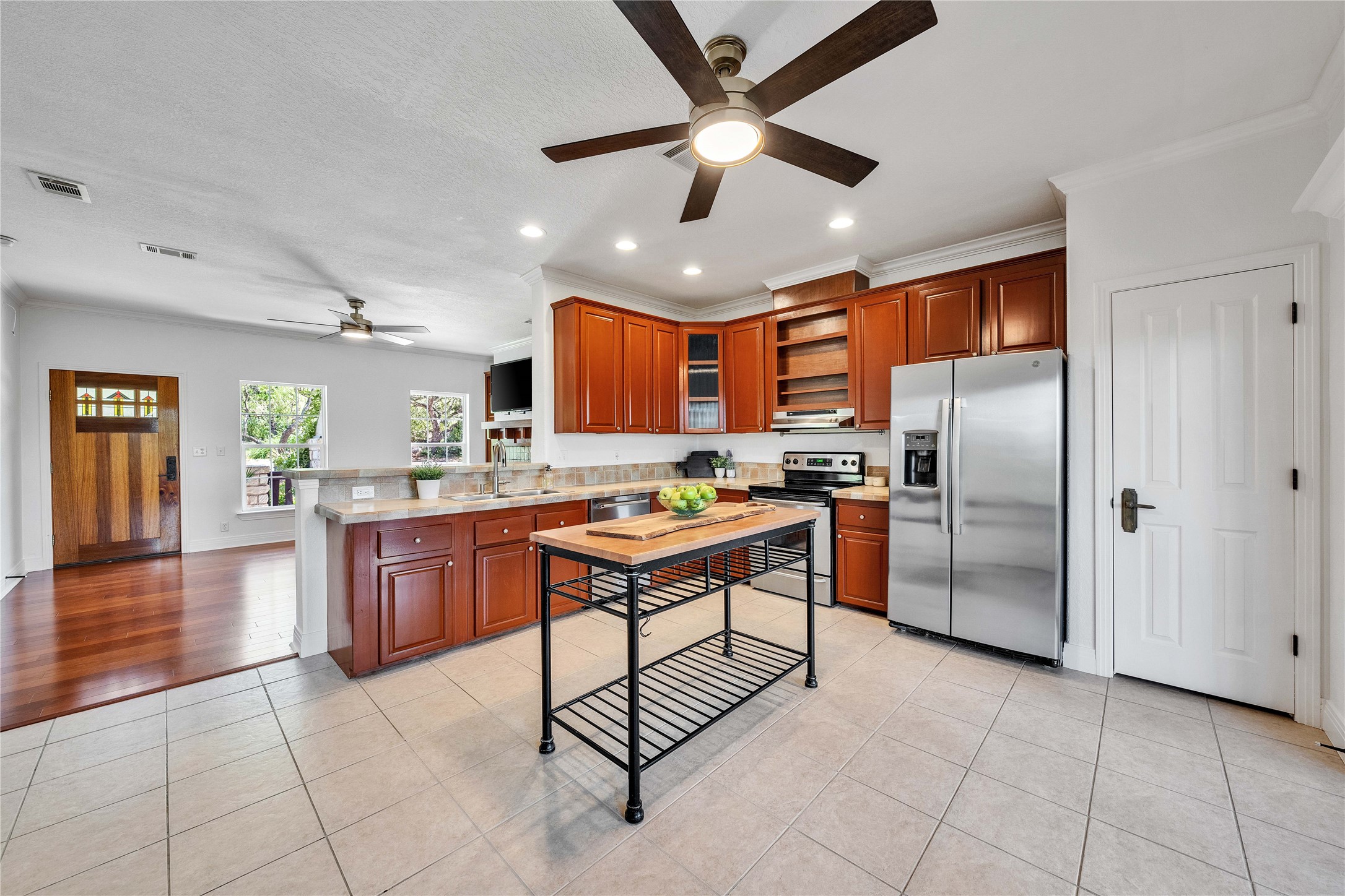 2108 Indian Creek Road Austin, TX 78734 - Photo 7 of 40 Kitchen with ceiling fan, appliances with stainless steel finishes, a peninsula, brown cabinetry, and light tile patterned floors