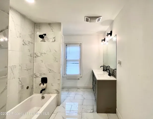a bathroom with a bathtub sink and mirror