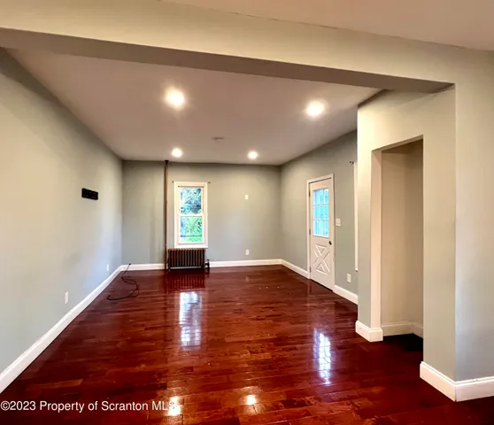 a view of an empty room with wooden floor and window