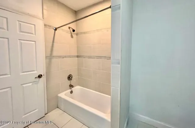 a bathroom with a tub a shower and a window