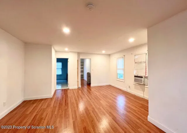 a view of an empty room with wooden floor and a window