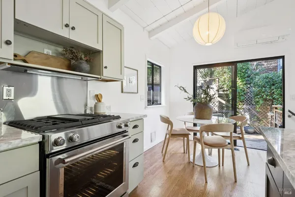 a kitchen with stainless steel appliances granite countertop a stove a sink dishwasher and white cabinets with wooden floor