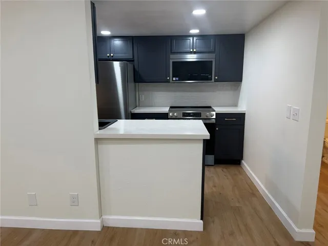 a kitchen with a refrigerator a stove top oven and wooden floor