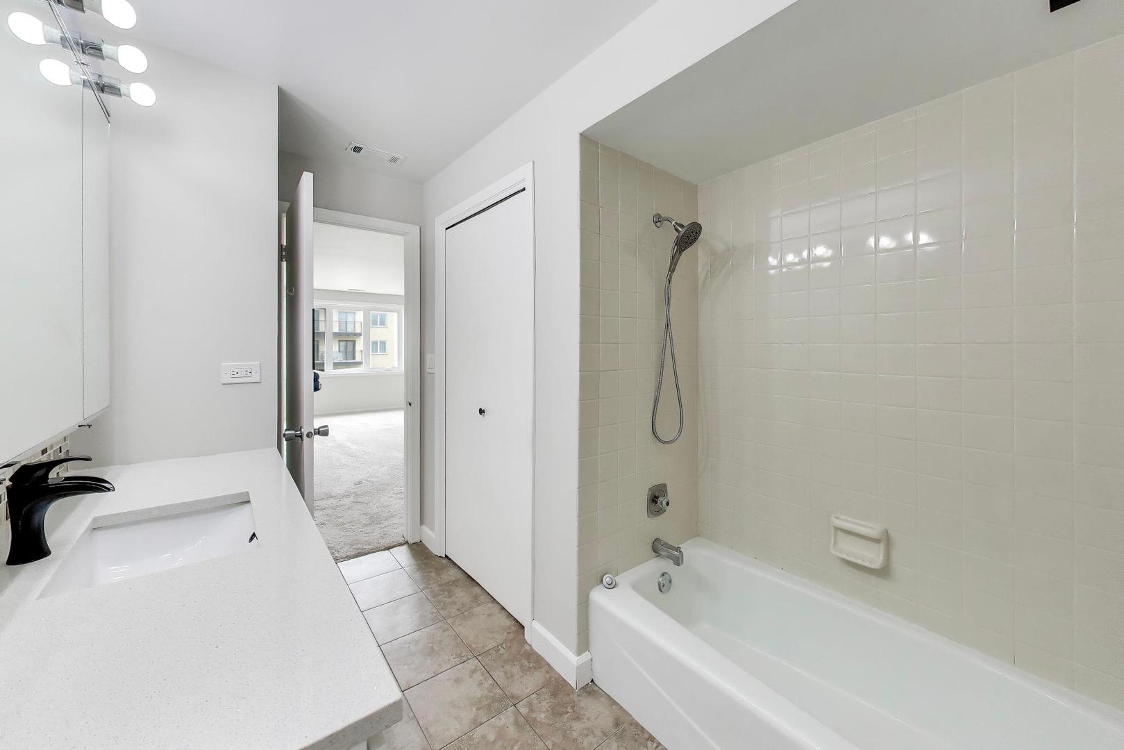 8610 Waukegan Road, Unit 302 Morton Grove, IL 60053 - Photo 23 of 34 a bathroom with a tub a sink and mirror
