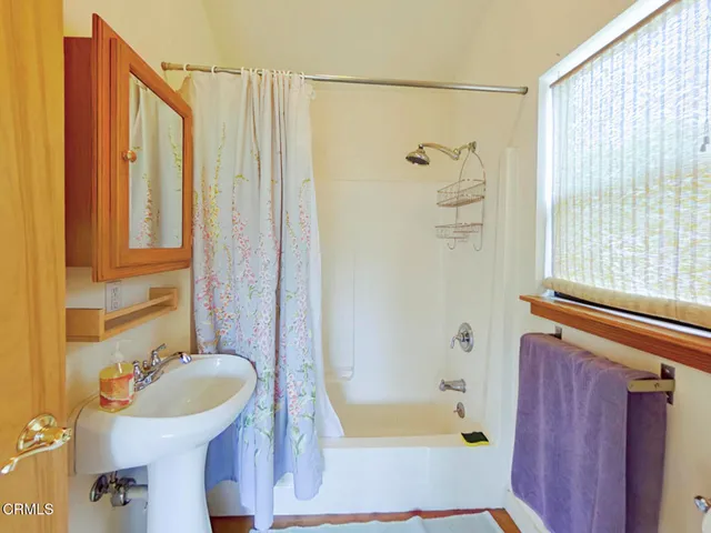 a view of a hallway with bathroom and wooden floor