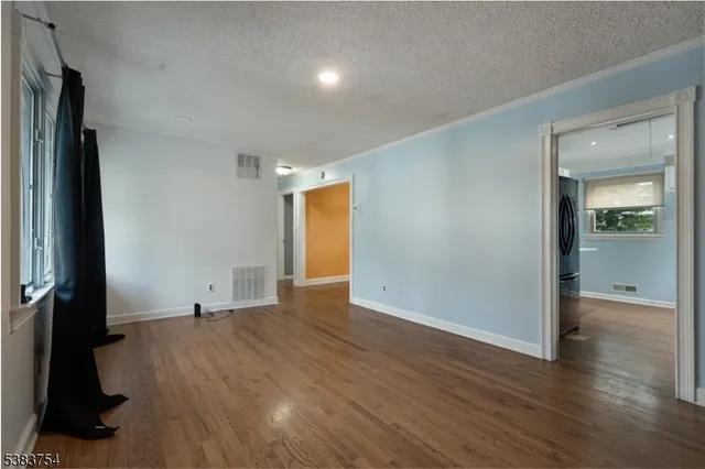 a view of an empty room with wooden floor and a ceiling fan