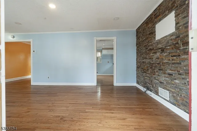 a view of an empty room with wooden floor and a bathroom