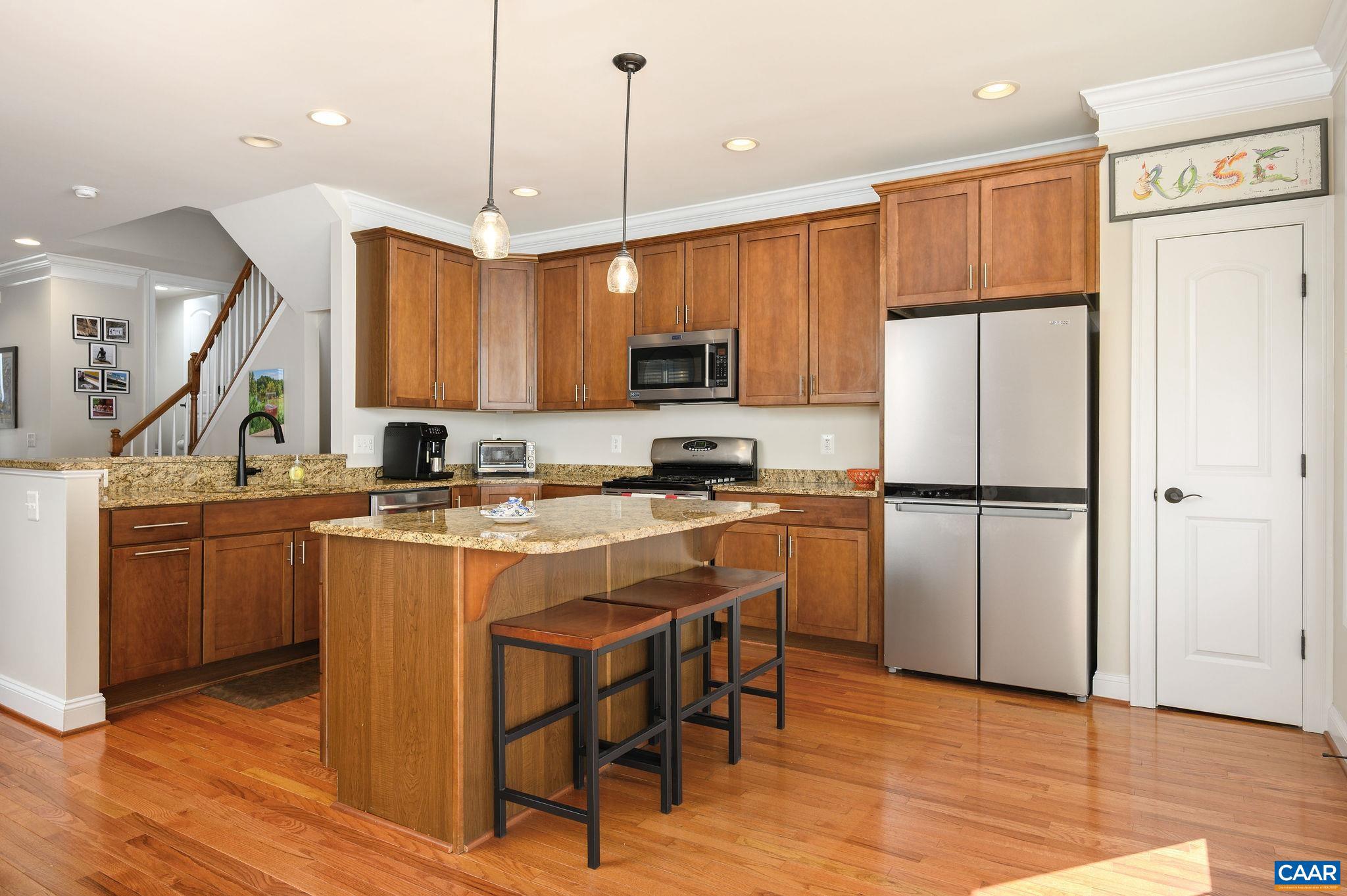 508 Tulip Tree Court Charlottesville, VA 22903 - Photo 12 of 35 a kitchen with kitchen island granite countertop wooden floors white cabinets and stainless steel appliances
