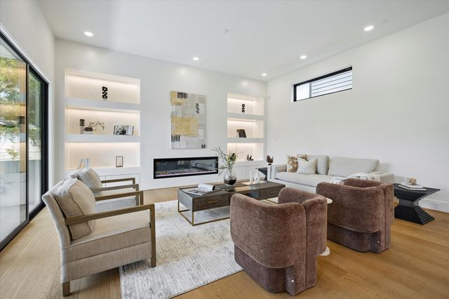 a living room with furniture a potted plant and kitchen view