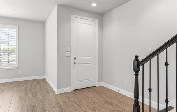 a view of an empty room with wooden floor and entryway