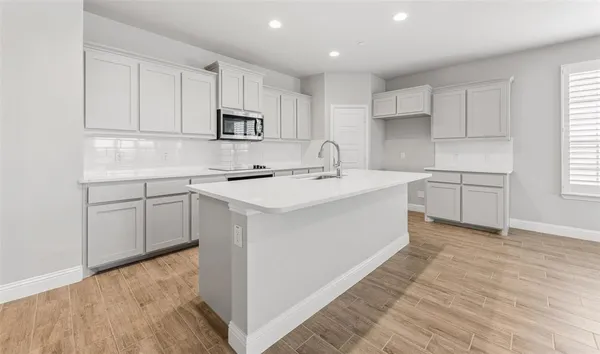 a kitchen with white cabinets appliances and sink