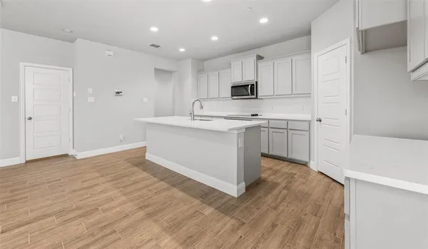 a kitchen with stainless steel appliances granite countertop a white stove top oven and white cabinets with wooden floor