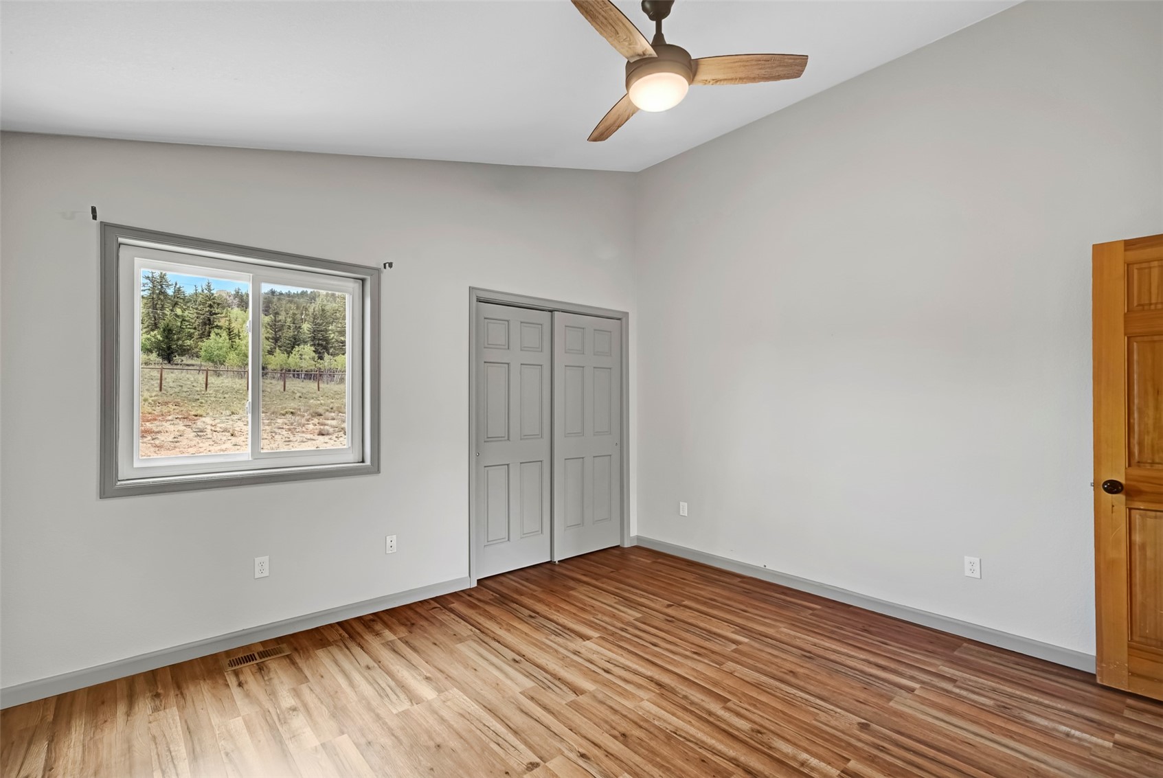 2491 Stagestop Road Jefferson, CO 80456 - Photo 17 of 43 an empty room with wooden floor chandelier fan and windows
