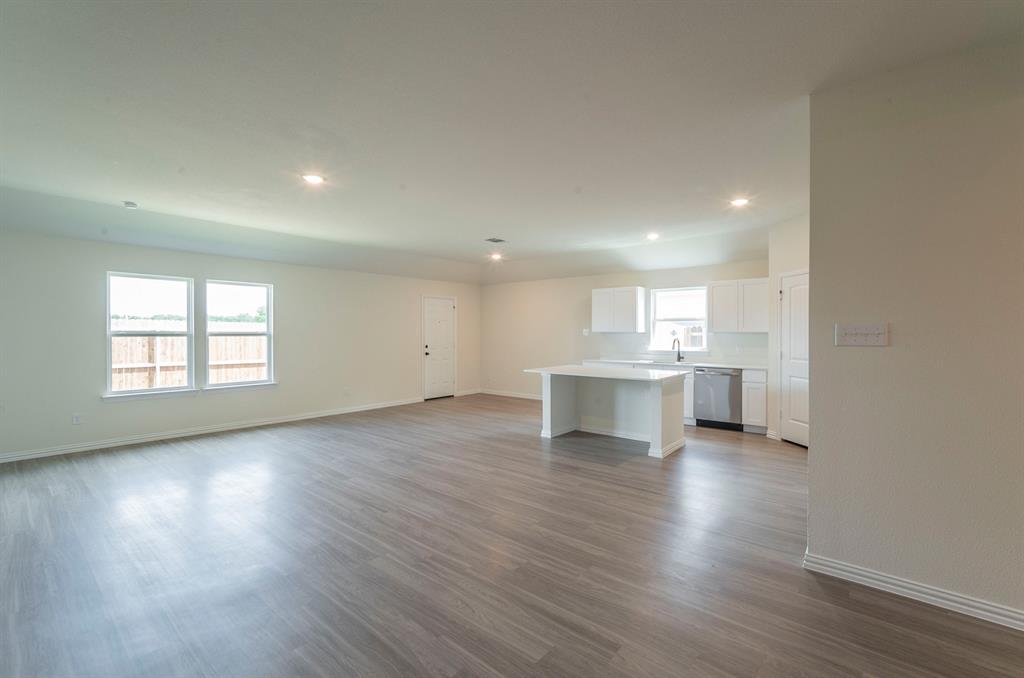 404 Rose Avenue Cleburne, TX 76033 - Photo 3 of 14 a view of an empty room and a kitchen with wooden floor