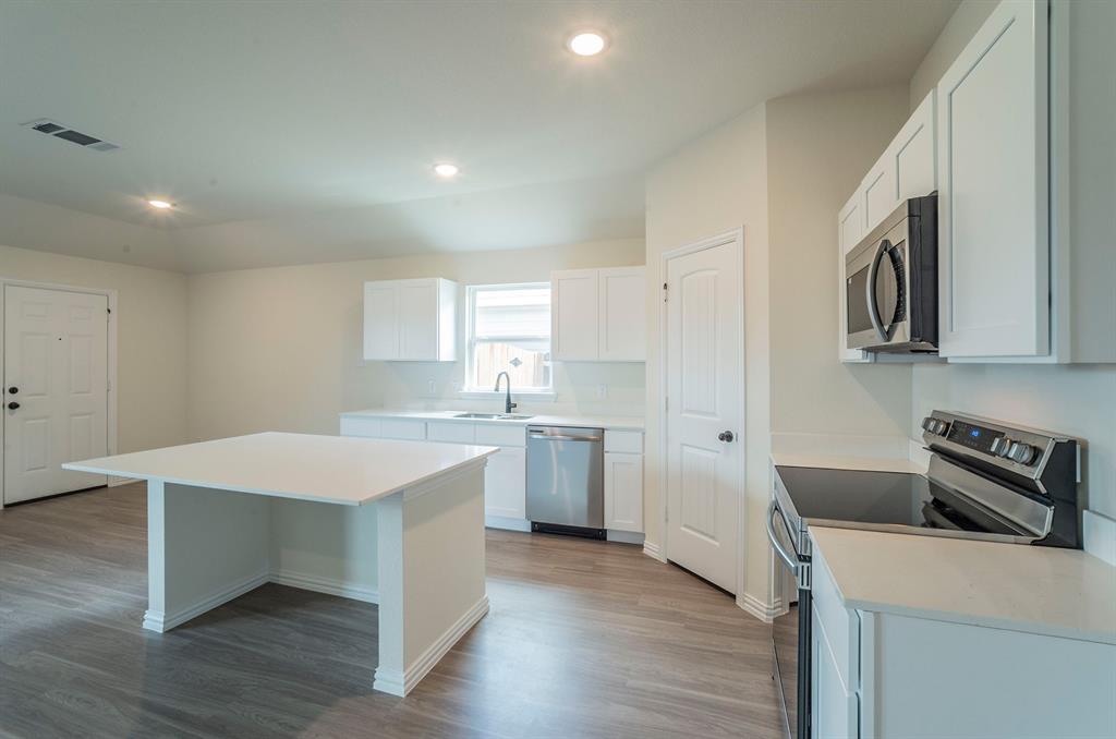 404 Rose Avenue Cleburne, TX 76033 - Photo 6 of 14 a kitchen with a sink dishwasher a stove and white cabinets with wooden floor