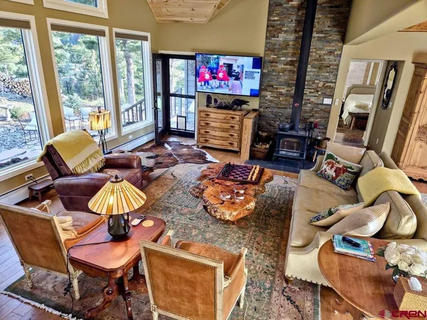 a living room with furniture a flat screen tv and a floor to ceiling window