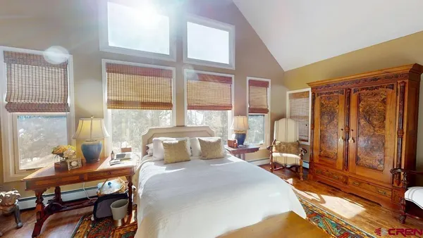 a bedroom with a bed and large windows