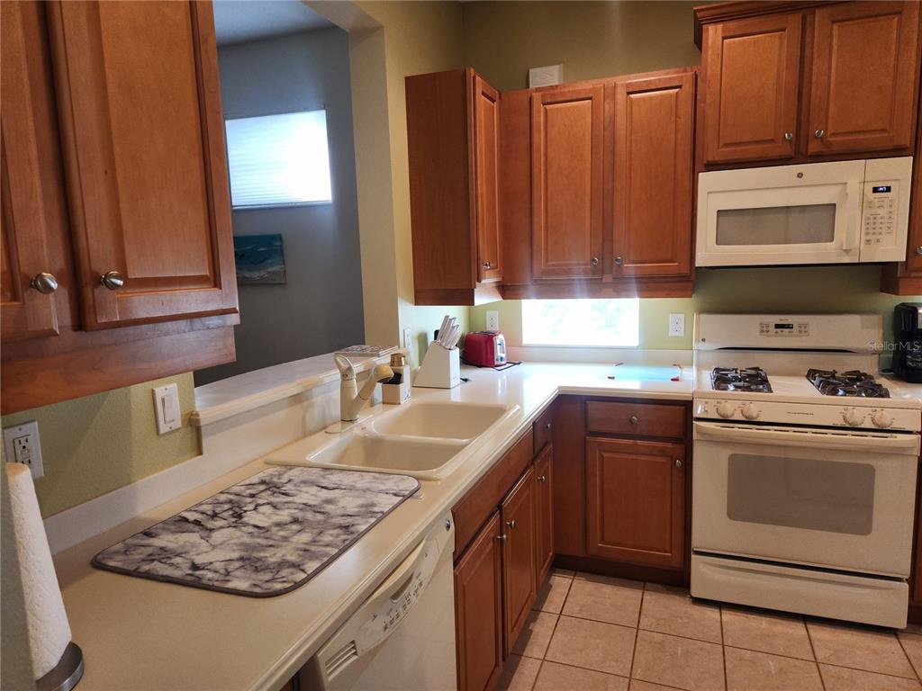 6642 Tailfeather Way Bradenton, FL 34203 - Photo 9 of 28 a kitchen with kitchen island granite countertop a sink stove and cabinets