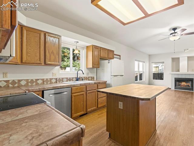 7590 Julynn Road Colorado Springs, CO 80919 - Photo 12 of 44 Kitchen featuring light wood-type flooring, dishwasher, sink, a center island, and white refrigerator