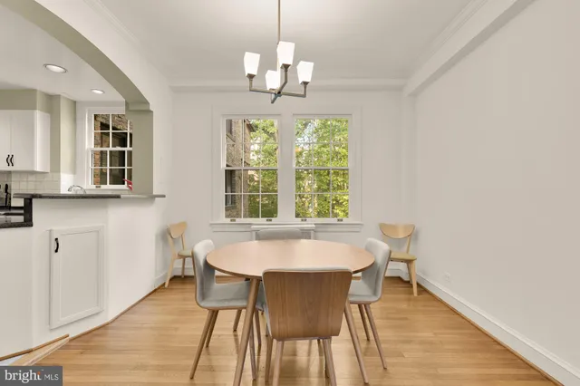a dining room with wooden floor a chandelier a wooden table and chairs