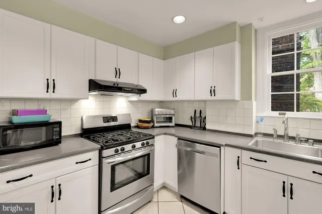 a kitchen with granite countertop white cabinets stainless steel appliances and a sink