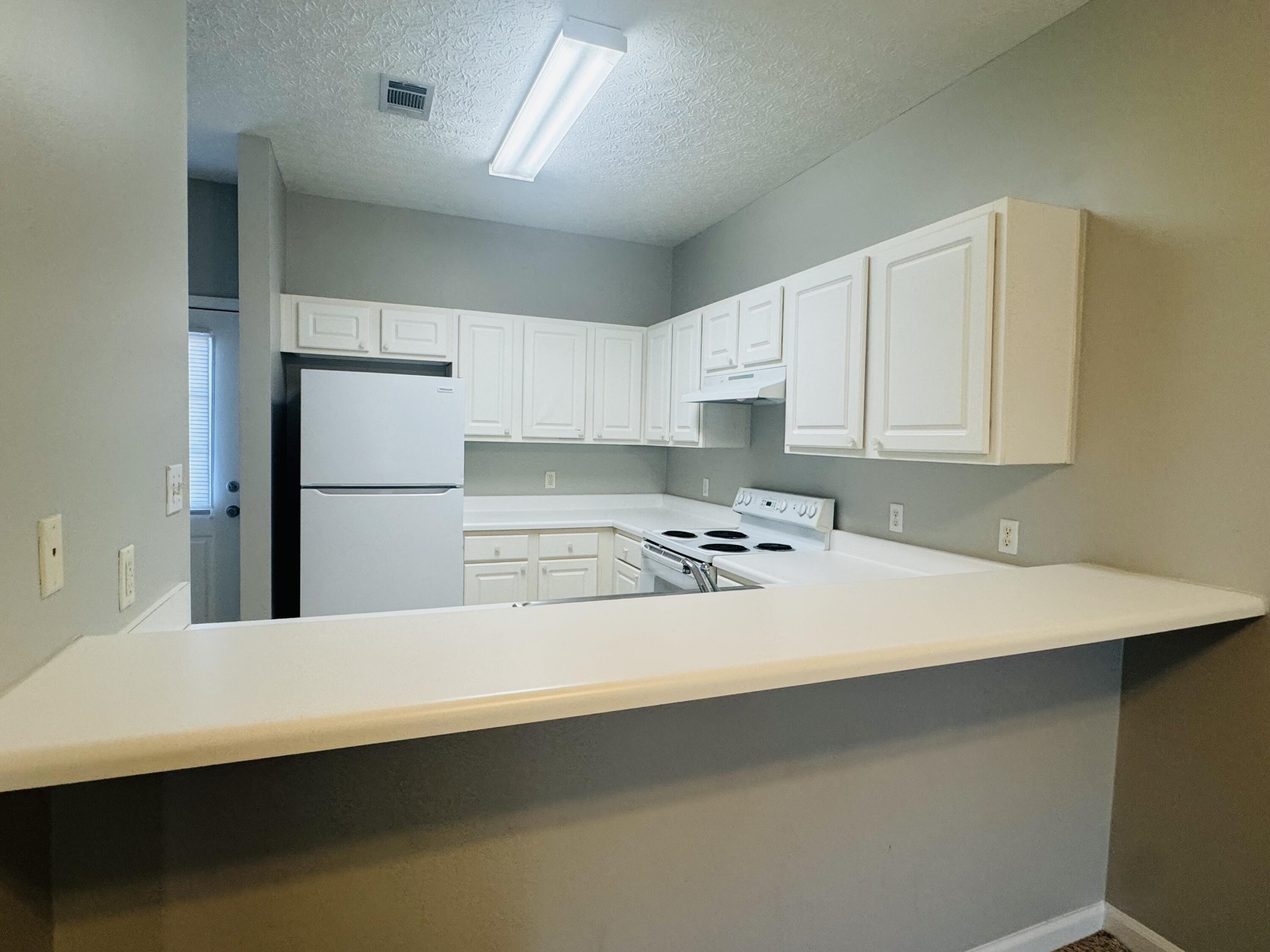34 Heron's Watch Way, Unit 3202 Santa Rosa Beach, FL 32459 - Photo 3 of 15 a kitchen with a sink a refrigerator and white cabinets