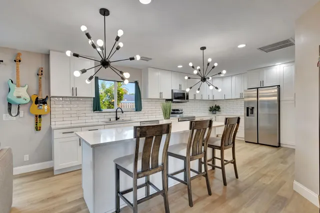 a kitchen with stainless steel appliances kitchen island granite countertop a dining table chairs and chandelier