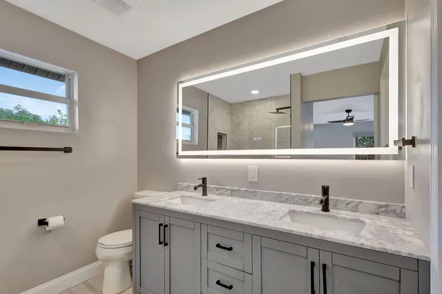 a bathroom with a granite countertop sink a toilet and a mirror