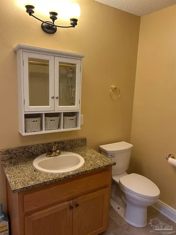 a bathroom with a granite countertop sink toilet and a mirror