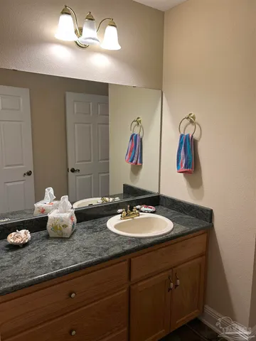 a bathroom with a sink granite and white cabinets