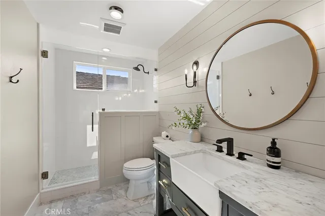 a bathroom with a granite countertop toilet a sink and a mirror