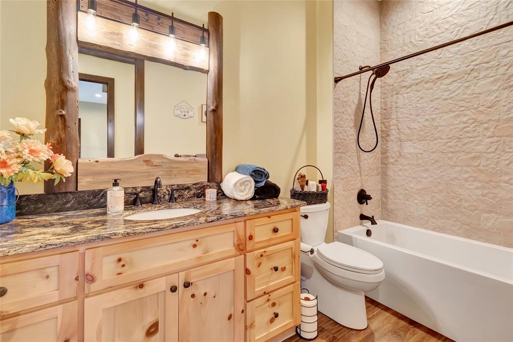 7330 Crabgrass Road St. Cloud, FL 34773 - Photo 20 of 60 a bathroom with a granite countertop sink a toilet and a bathtub