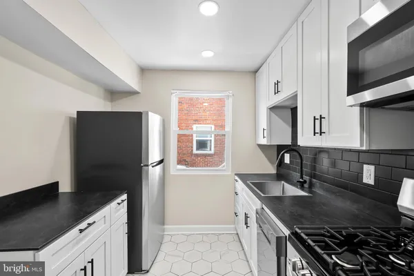 a kitchen with granite countertop a sink stove and refrigerator