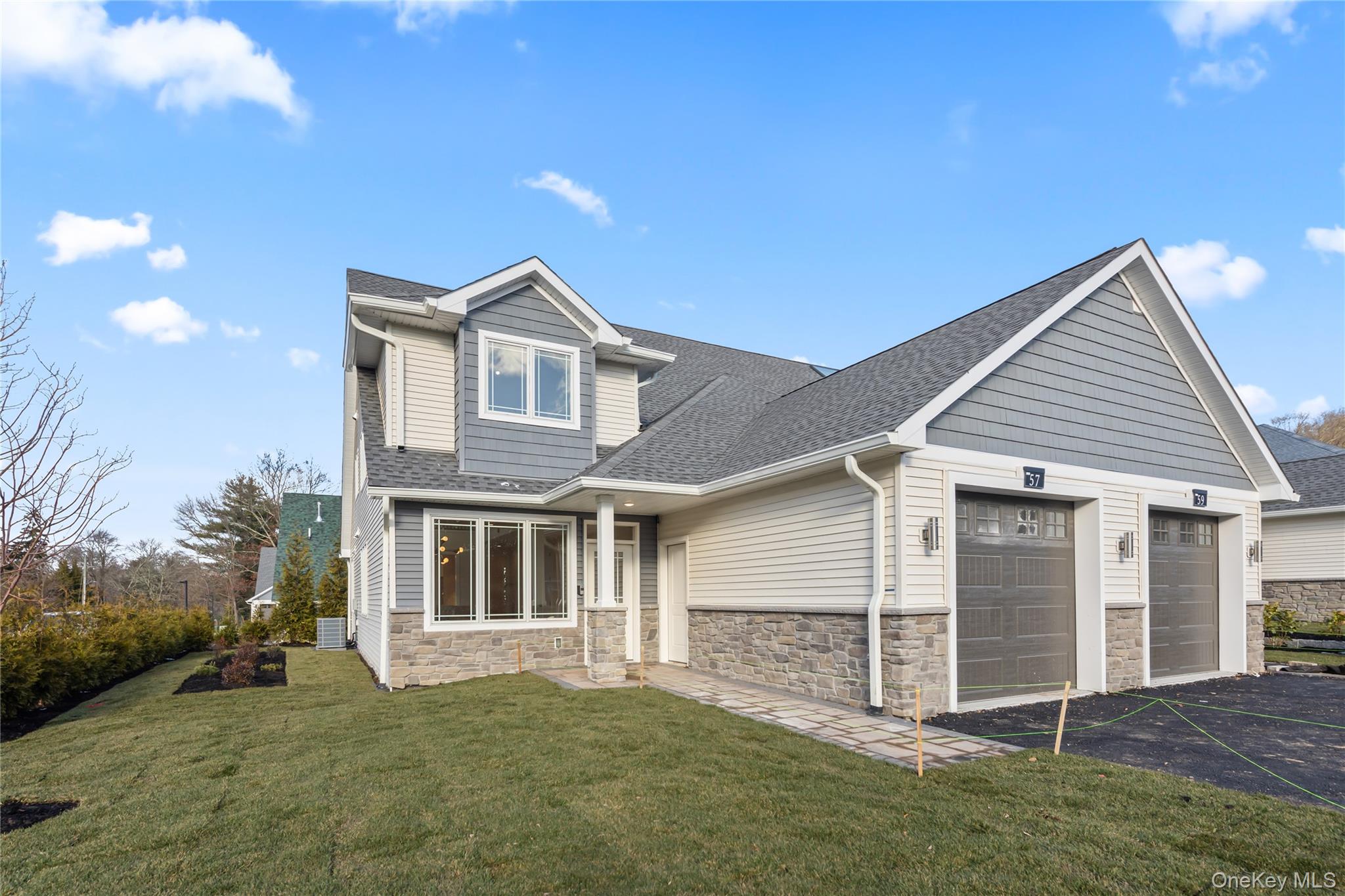 19 Dessau Circle Spring Valley, NY 10977 - Photo 1 of 48 View of front facade with roof with shingles, stone siding, an attached garage, asphalt driveway, and a front lawn