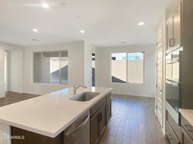 a kitchen with stainless steel appliances a sink a stove a refrigerator cabinets and a large window