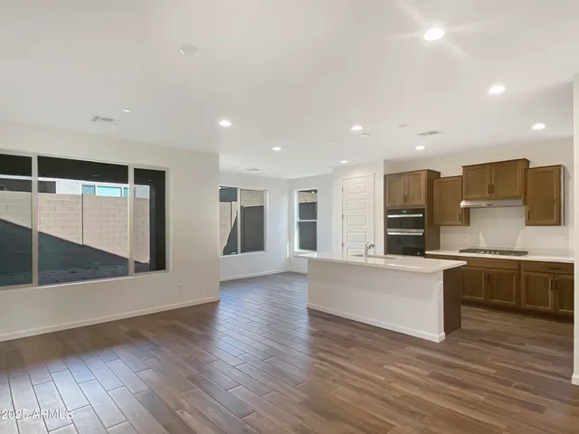 a view of kitchen with stainless steel appliances wooden floor and large window