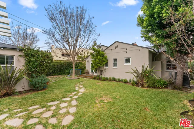 a view of a white house with a big yard and large trees