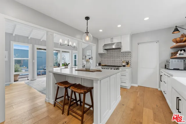 a kitchen with stainless steel appliances kitchen island granite countertop a table chairs sink and cabinets
