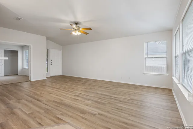 a view of empty room with wooden floor and fan