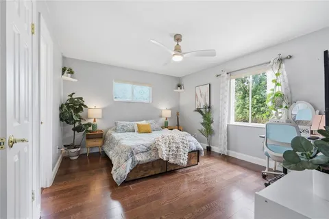 a bedroom with a bed table flowerpot and window