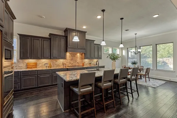 a kitchen with granite countertop a dining table chairs sink and wooden floor