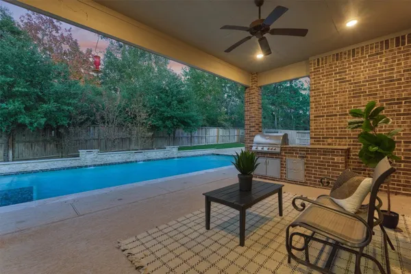 a view of a backyard with table and chairs potted plants and a large tree