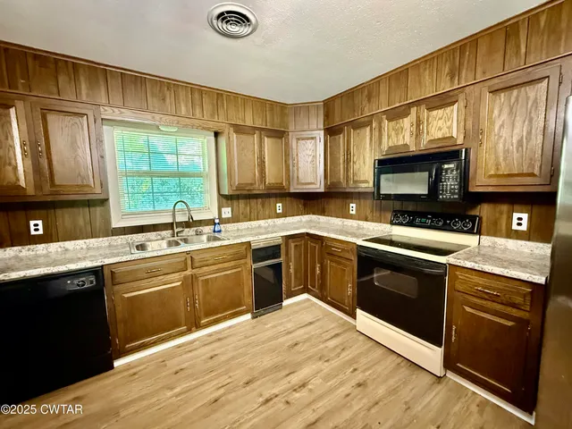 a kitchen with stainless steel appliances granite countertop a stove a sink dishwasher and a microwave oven with cabinets