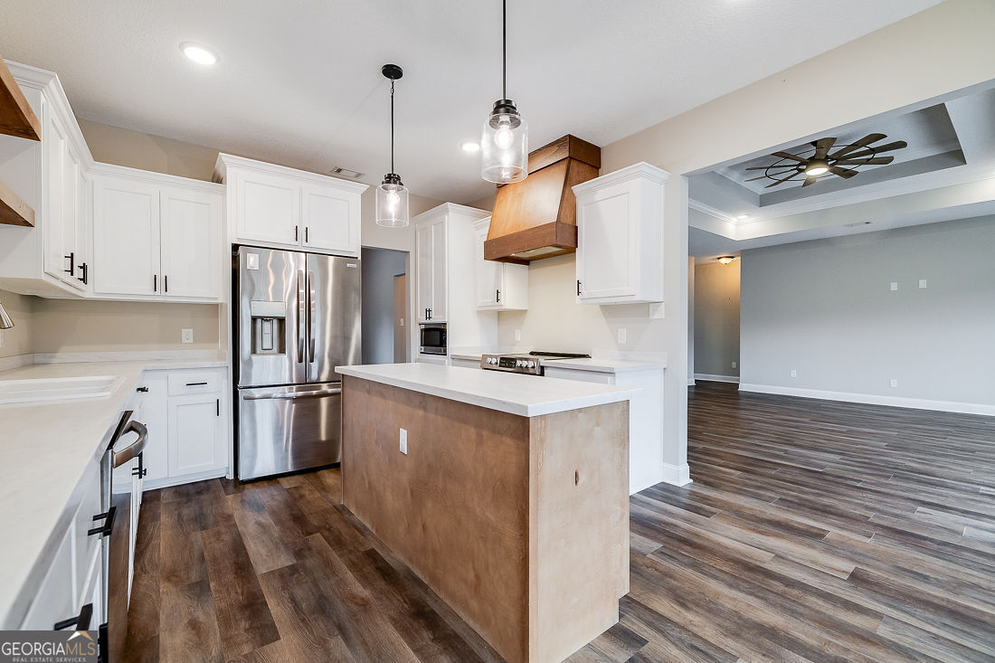 127 Winding Way Road Pembroke, GA 31321 - Photo 13 of 38 a kitchen with refrigerator a stove and white cabinets with wooden floor