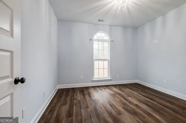an empty room with wooden floor cabinet and windows