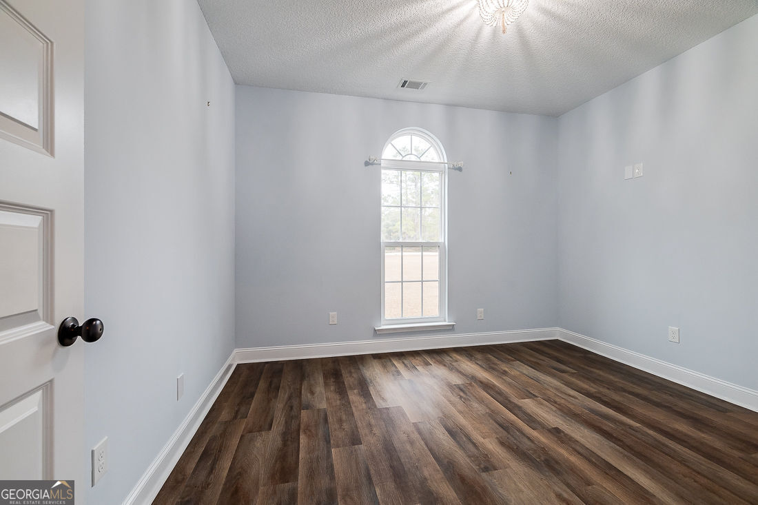 127 Winding Way Road Pembroke, GA 31321 - Photo 26 of 38 an empty room with wooden floor cabinet and windows