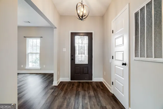 an empty room with wooden floor cabinet and mirror