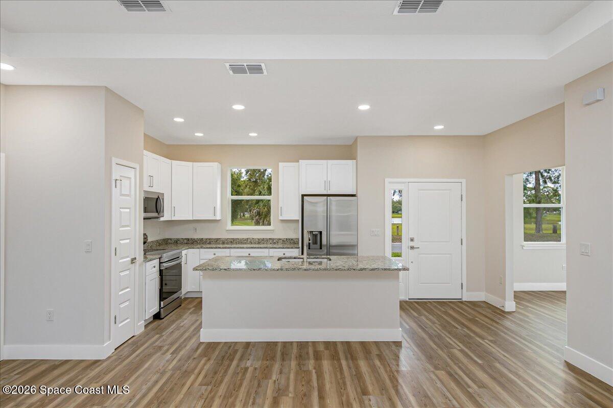 958 Chace Lane Northeast Palm Bay, FL 32905 - Photo 3 of 27 a large kitchen with stainless steel appliances kitchen island granite countertop a large cabinets a sink and a stove