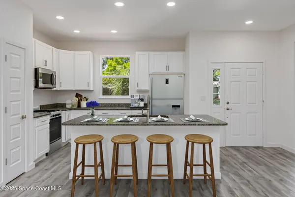 a large kitchen with stainless steel appliances kitchen island granite countertop a large cabinets a sink and a stove